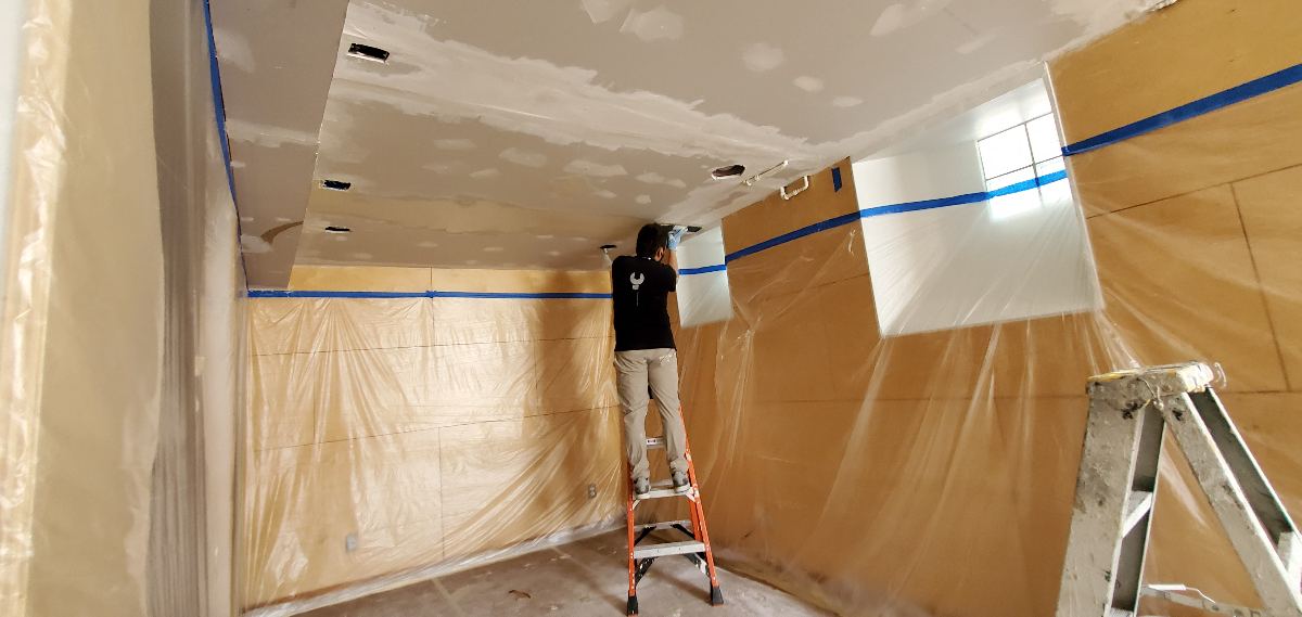 Ceiling skimcoating with adjacent areas protected